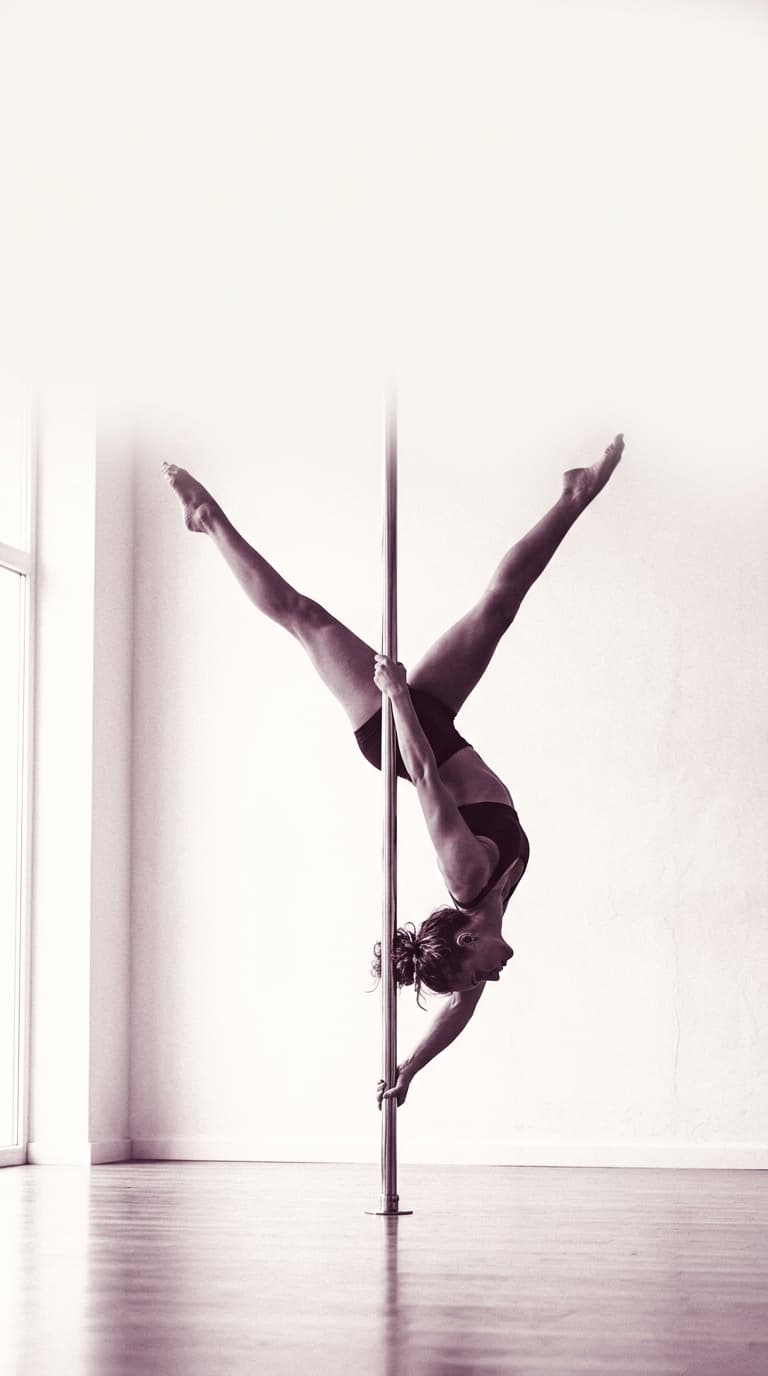 A StudioVeena dancer performing an invert on a pole